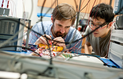 Professor working in a hardware lab with a Ph.D.student
