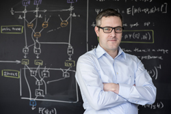 Male professor standing in front of a chalkboard with computer engineering figures and diagrams